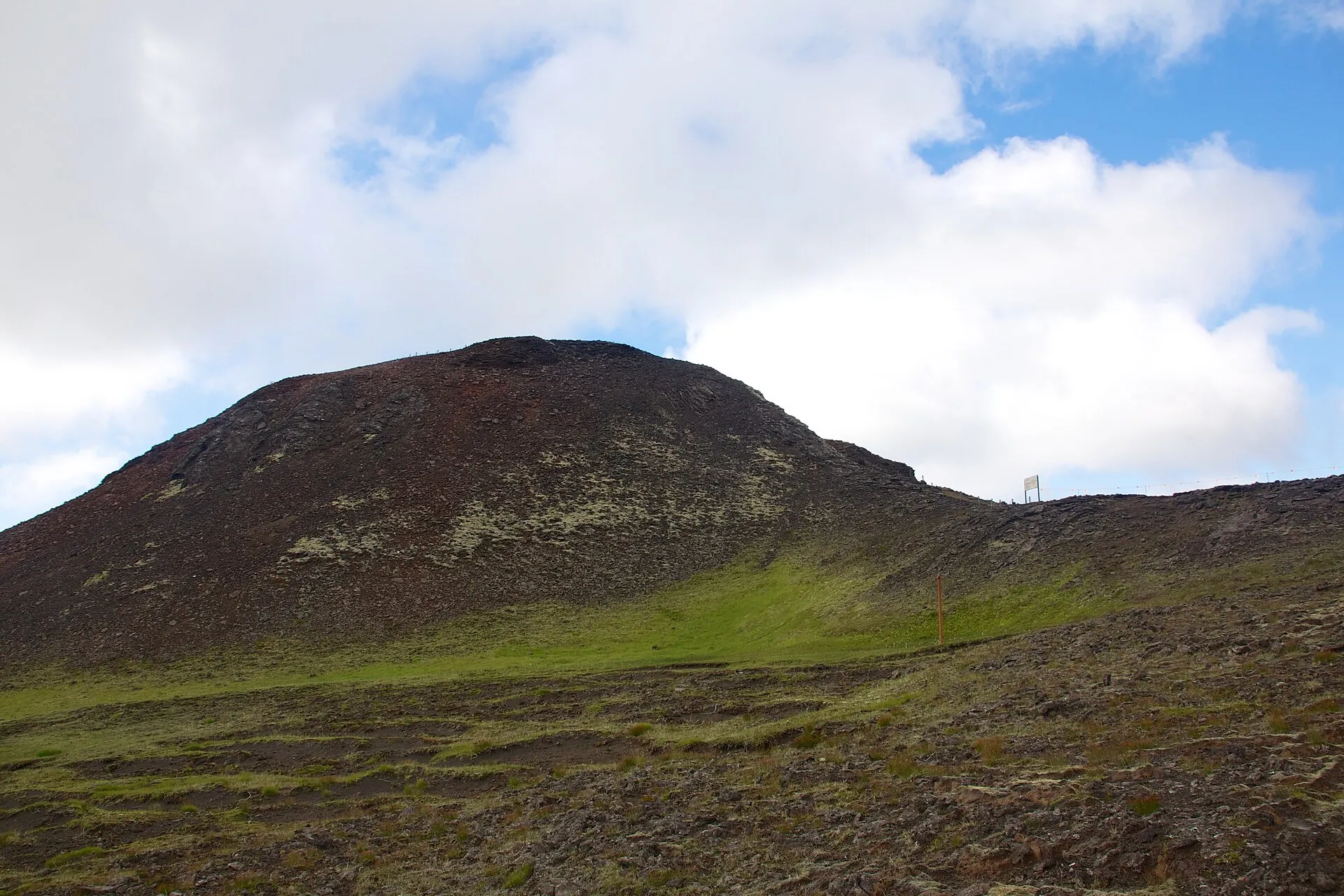 Der Schlackenkegel Þríhnúkagígur in den Bláfjöll: ein flacher brauner Hügel über moosigem Lavafeld, der Kraterschlund kaum zu erkennen