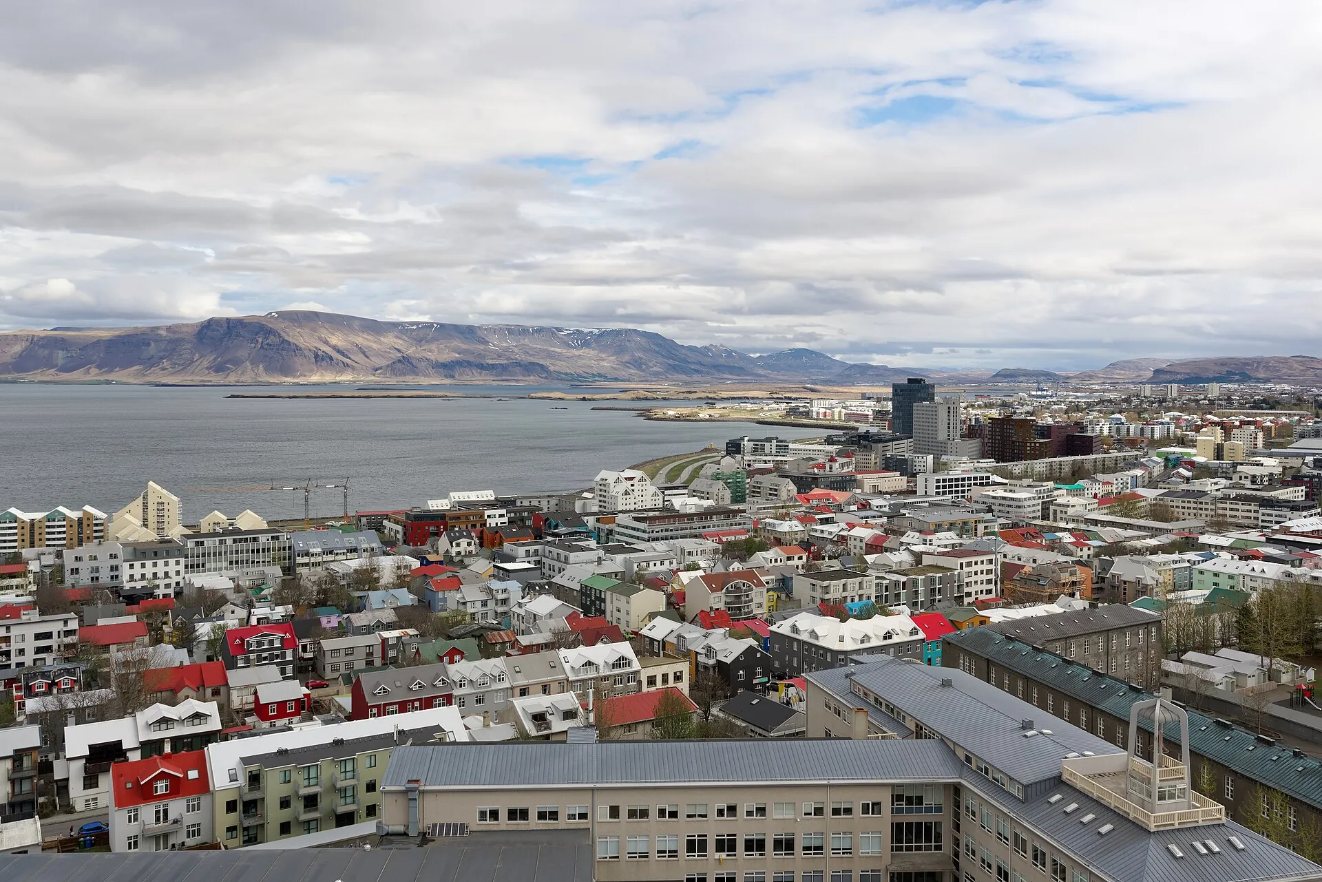 Blick von der Hallgrímskirkja über die bunten Dächer von Reykjavík zur Bucht und zu den Bergen dahinter