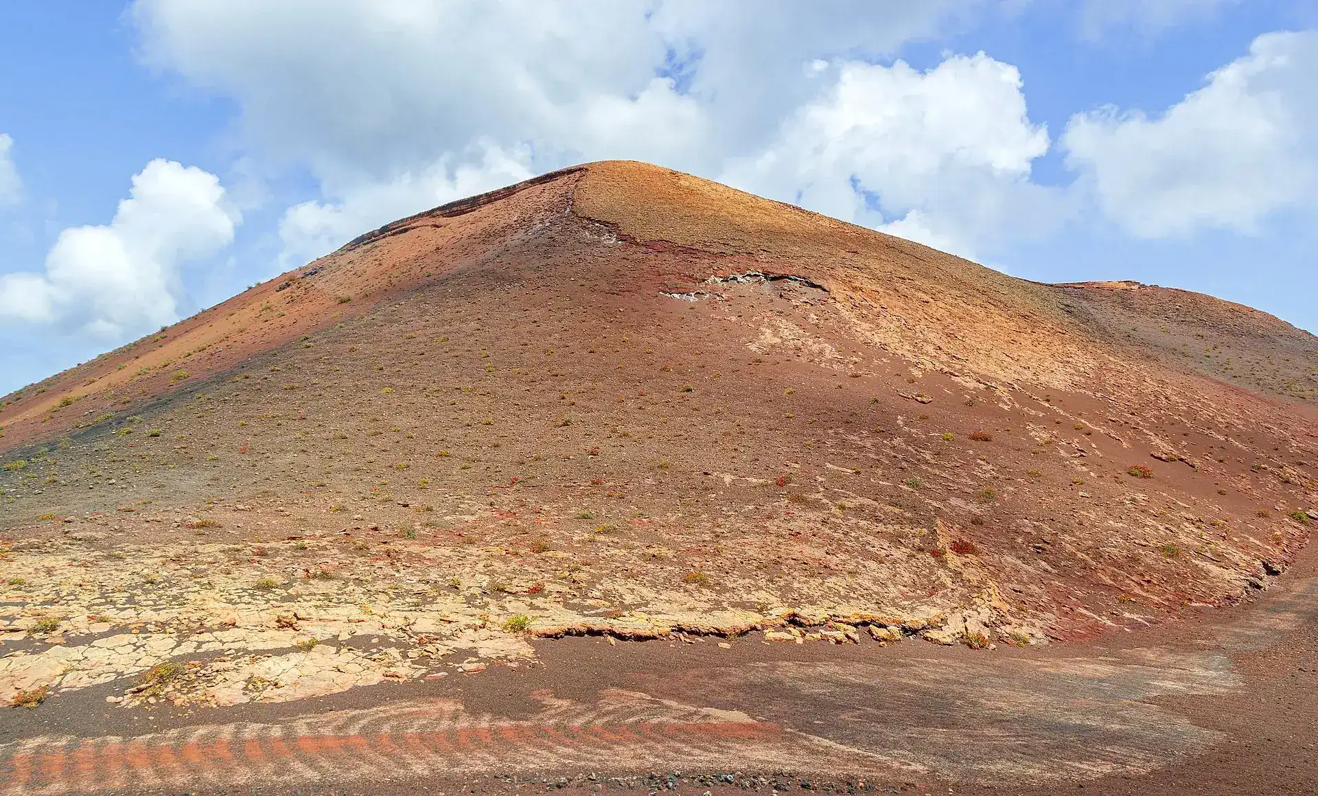 Ein rostroter Vulkankegel im Timanfaya-Nationalpark unter Passatwolken
