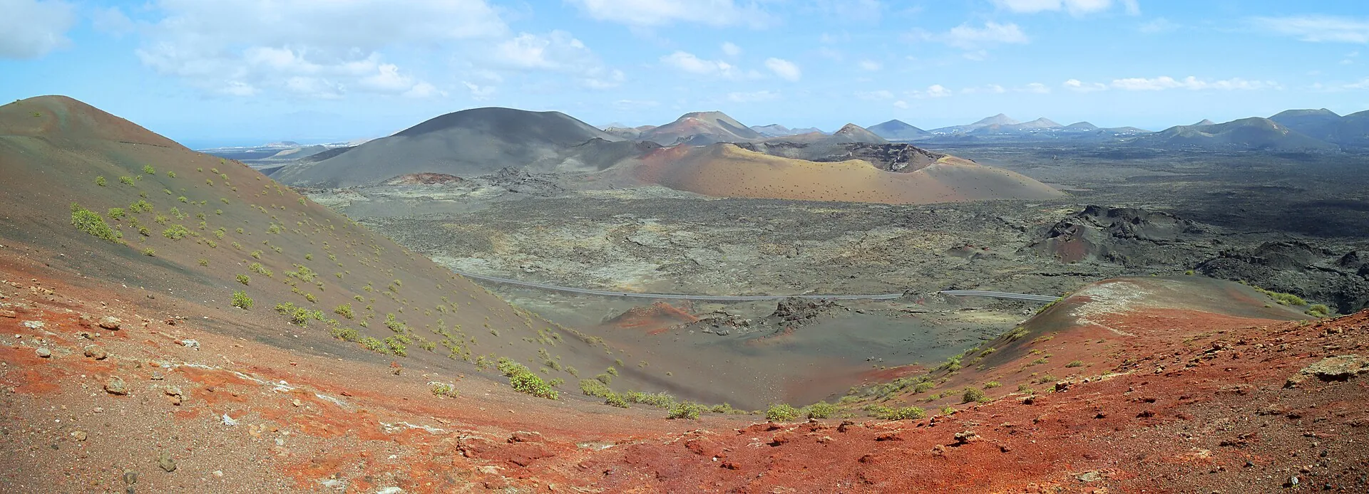 Panorama der Feuerberge im Nationalpark Timanfaya: rote und schwarze Vulkankegel, dazwischen Lavafelder