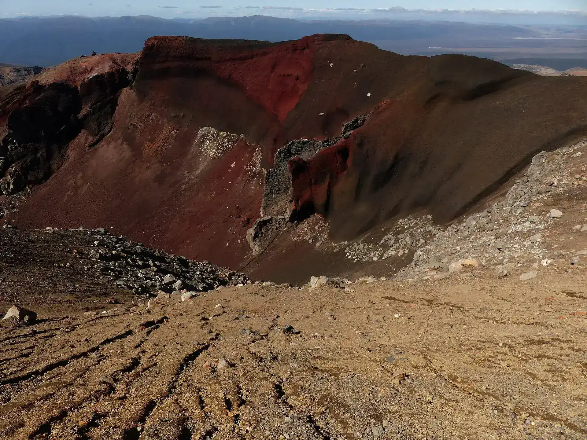 The Red Crater on Tongariro: a deeply cut, rust-red crater bowl with pale lapilli scree in the foreground