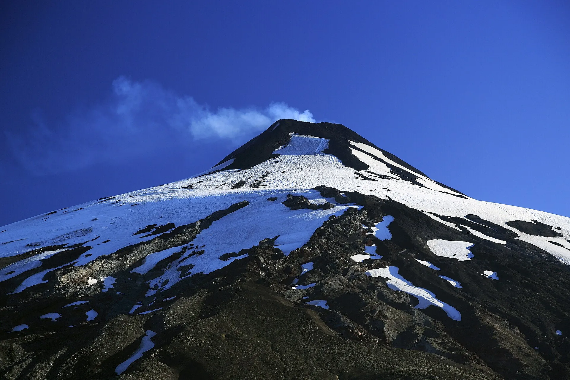 Der Gipfelaufbau des Villarrica aus der Nähe: Firn, dunkle Lavarippen und eine Dampfwolke über dem Kraterrand