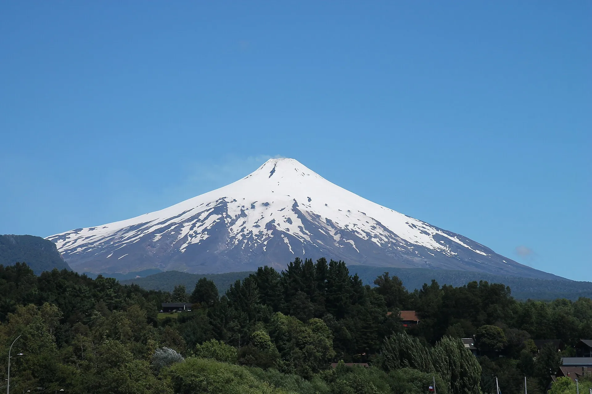 Der schneebedeckte Kegel des Villarrica über den Wäldern bei Pucón, eine kleine Dampffahne am Gipfel