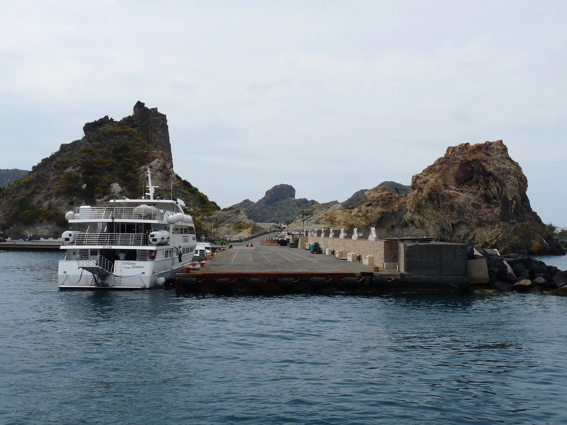 A hydrofoil moored at Porto di Levante on Vulcano, the Faraglione rock and the houses of the village behind