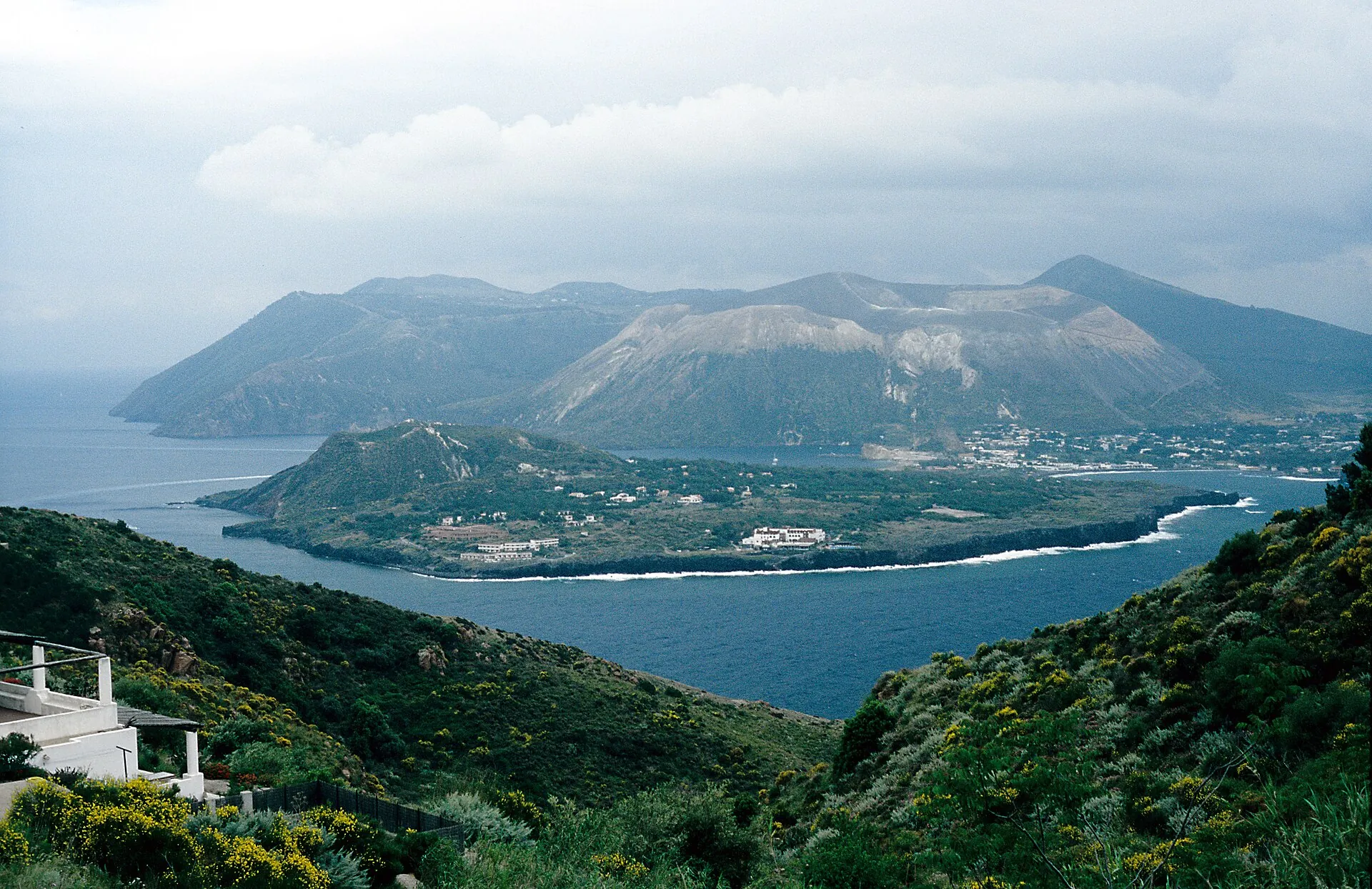 View from Lipari across to Vulcano: the Vulcanello peninsula in front, the pale cone of La Fossa with steam over the crater behind