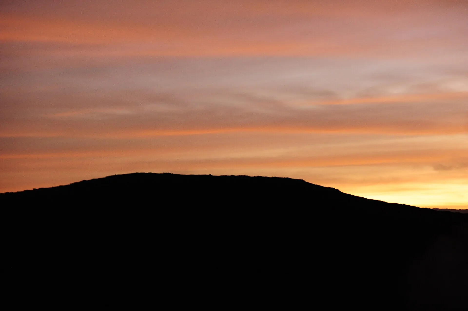 Der Krater des Mount Yasur in der Dämmerung: Rauch über dem Rand, der Himmel noch blau, der Boden schon dunkel